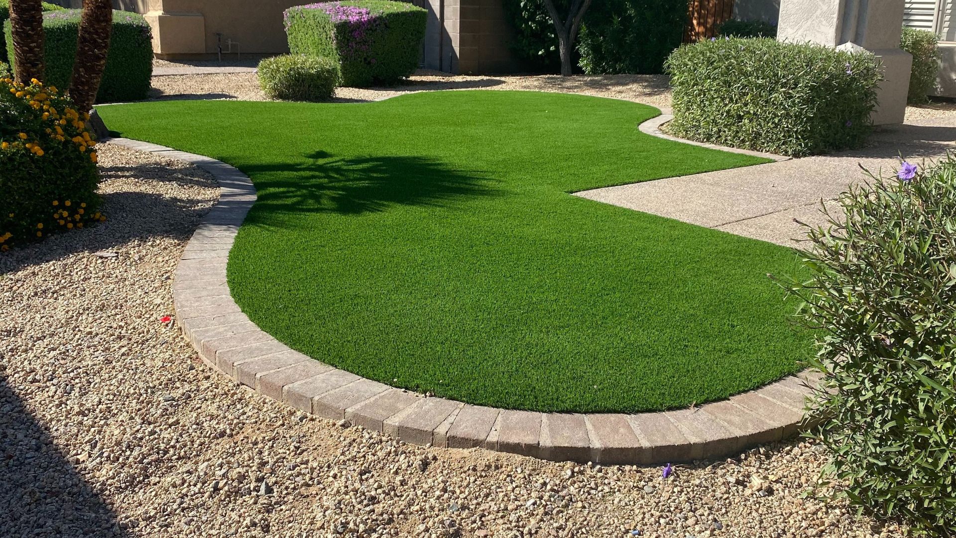 Curved artificial lawn with stone border.
