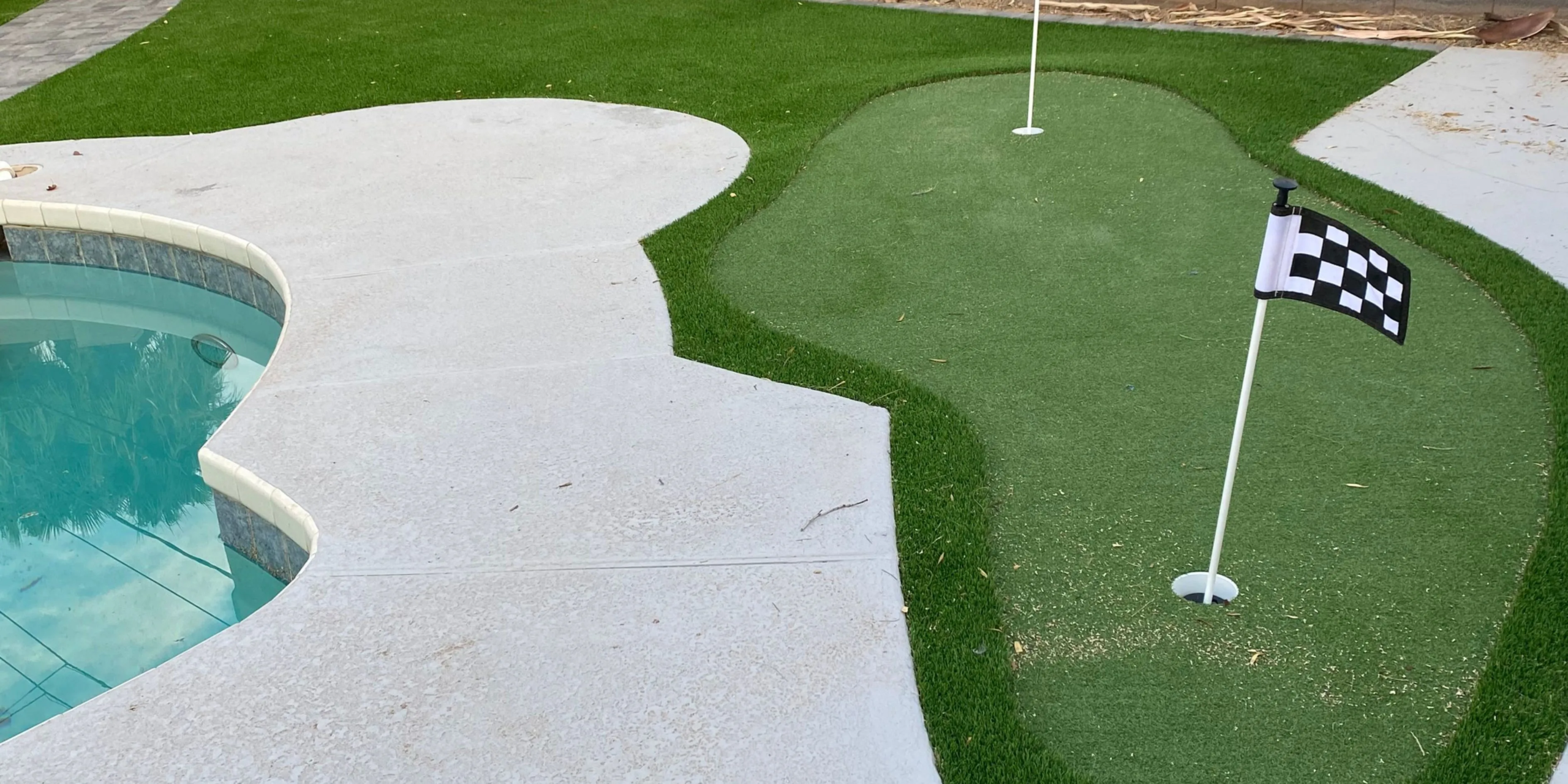 Backyard putting green beside pool