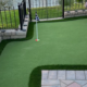 Backyard putting green with golf flags by a pond
