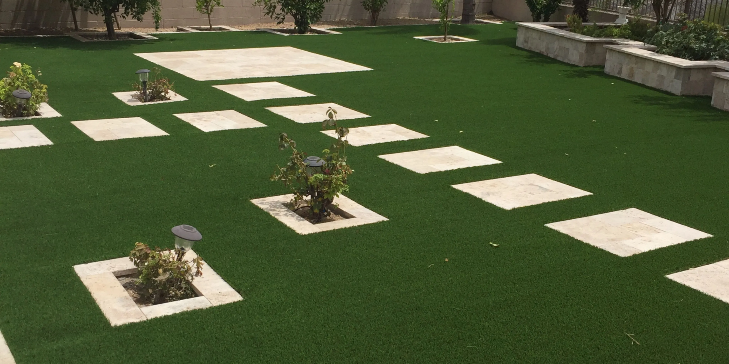 Modern backyard with turf and square stepping stones.