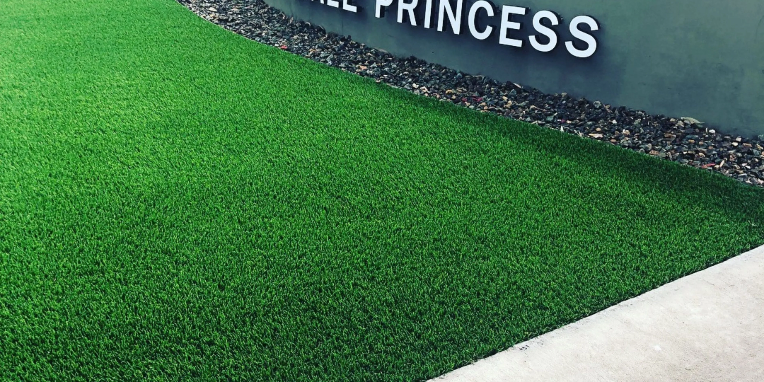 Artificial turf lawn beside building sign and gravel border