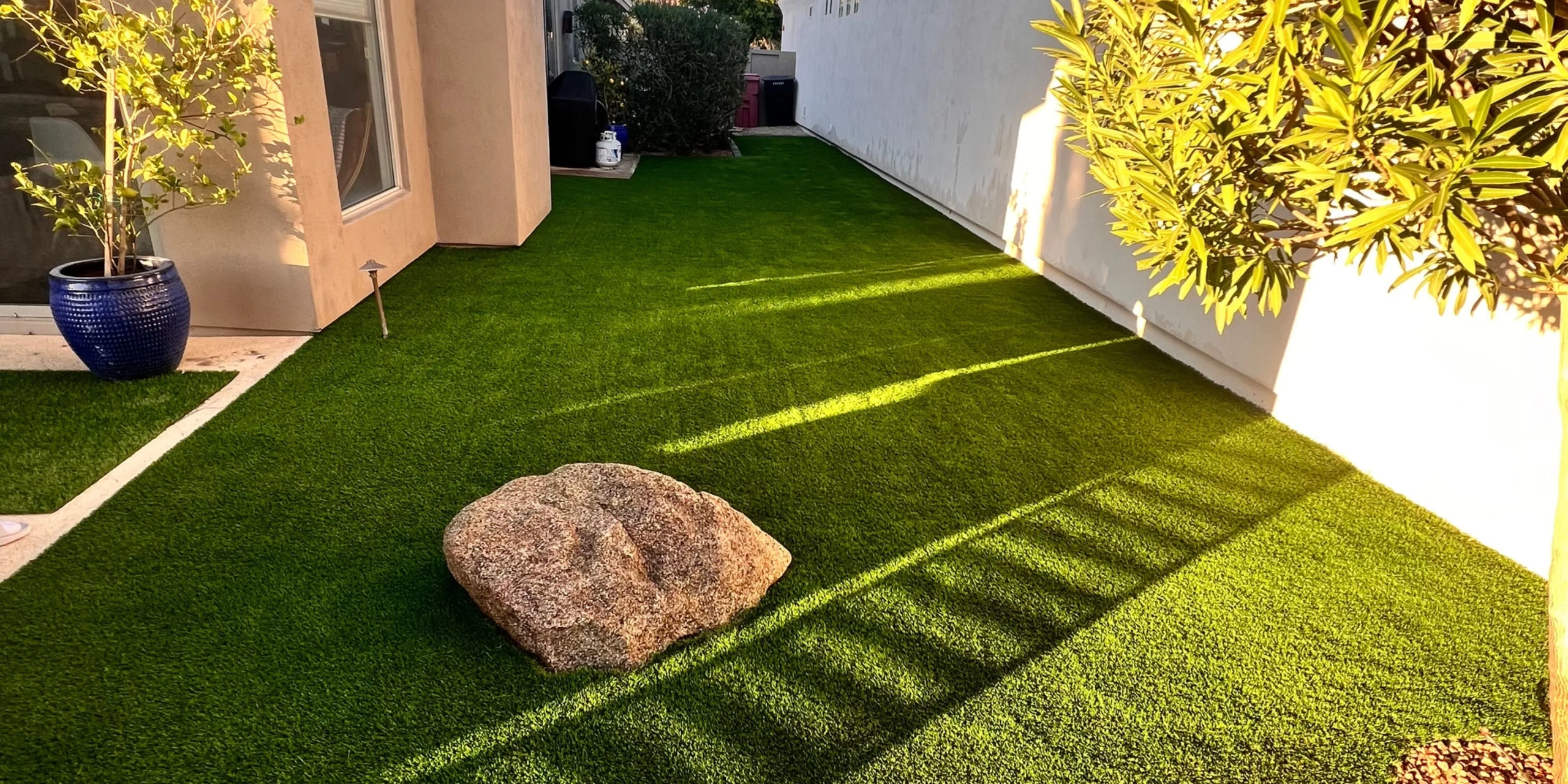 Artificial turf backyard side yard with decorative rock