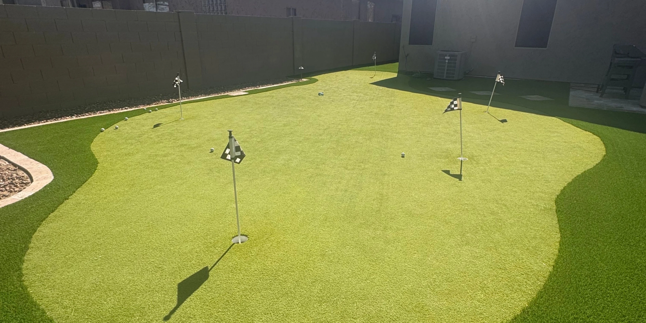Backyard artificial turf putting green with multiple holes