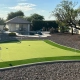 Backyard putting green with pool and patio area in a landscaped yard