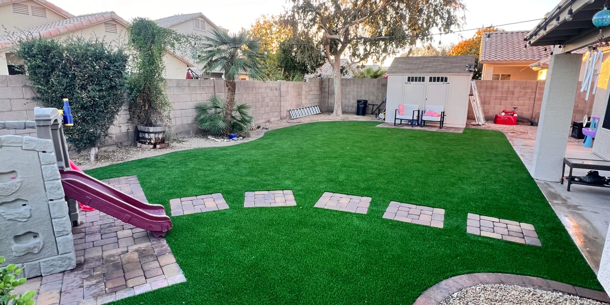 Backyard with artificial grass, stepping stones and kids slide