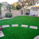Artificial turf backyard with stepping stones, slide, and shed