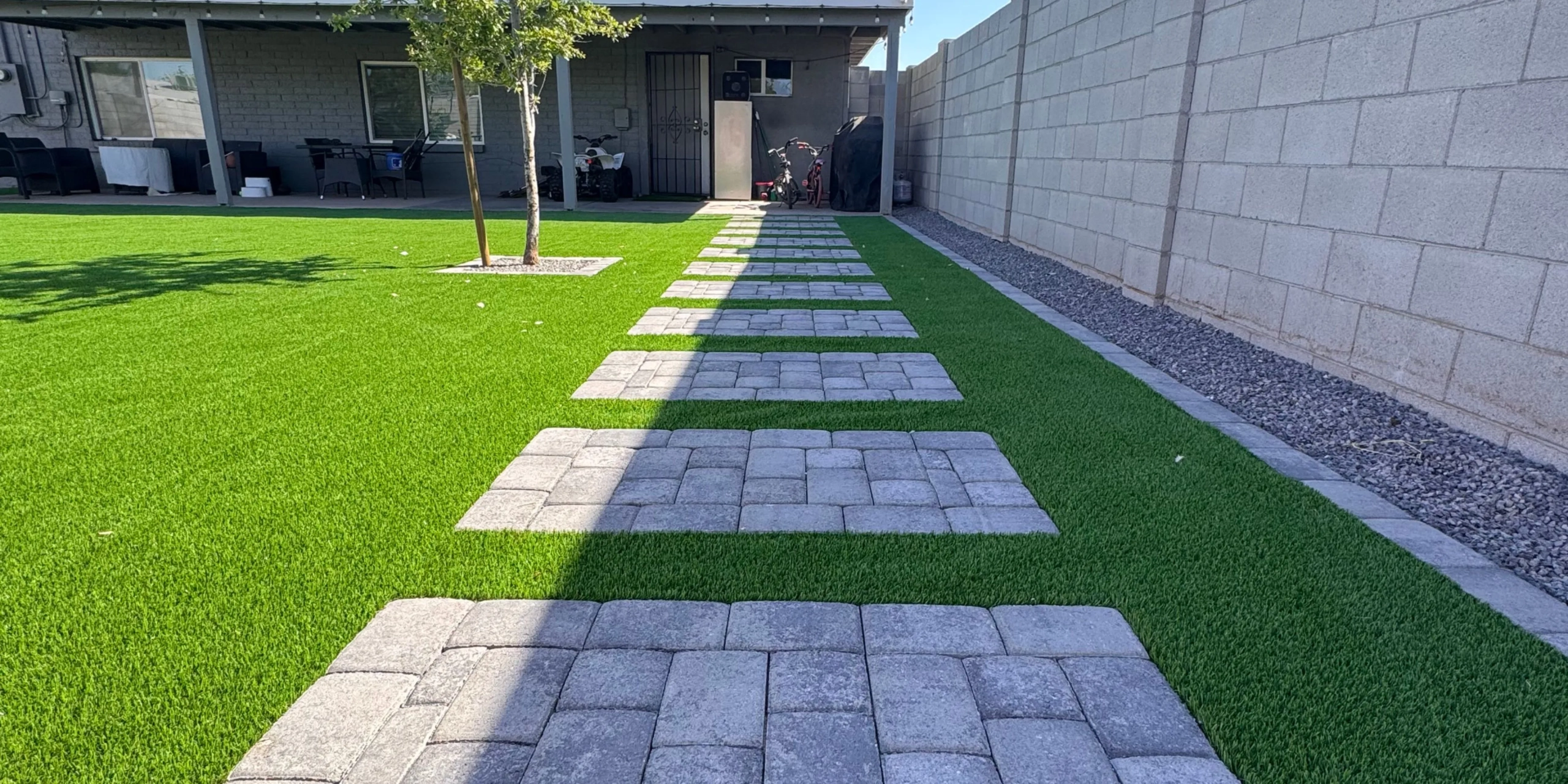 Stepping stone path across green lawn to covered patio
