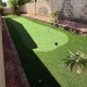Artificial grass backyard with a putting green