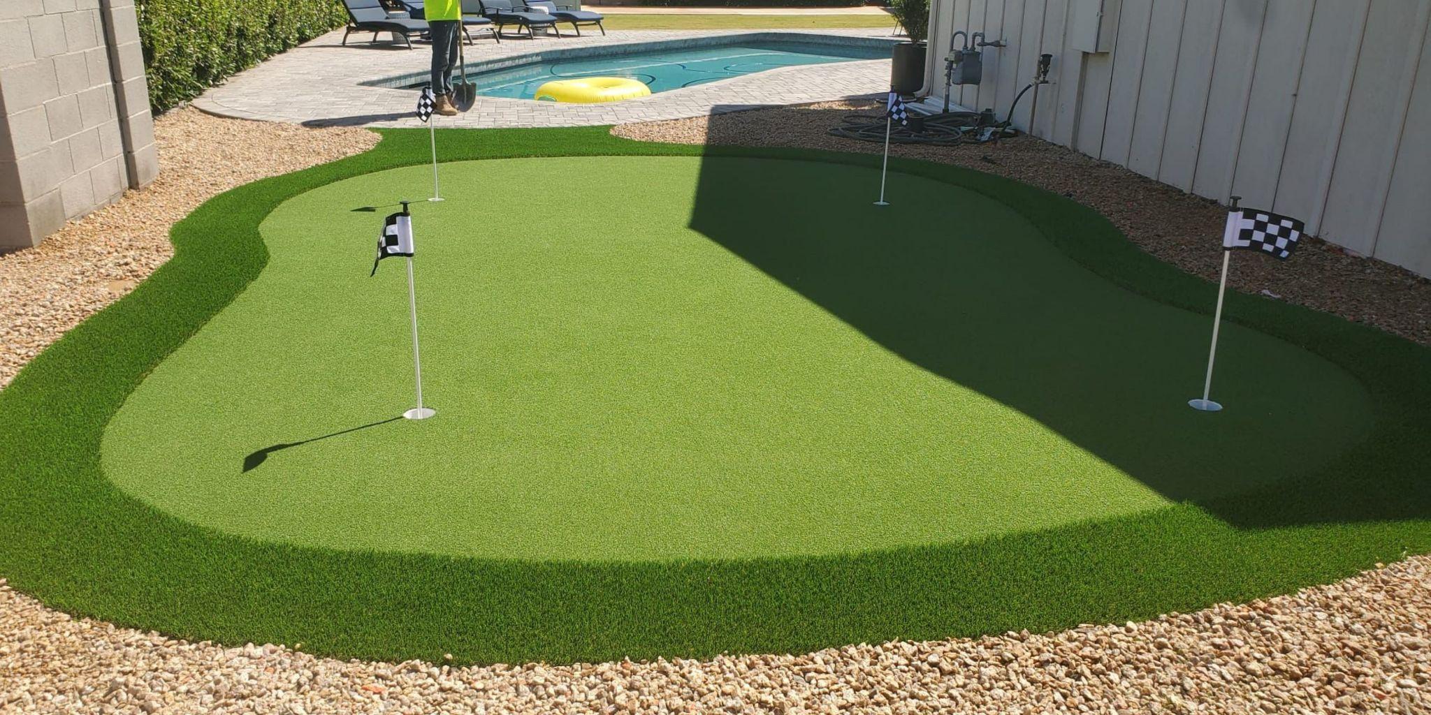Artificial grass putting green with three golf flags in a backyard