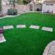 Backyard with artificial grass, stepping stones, a small slide