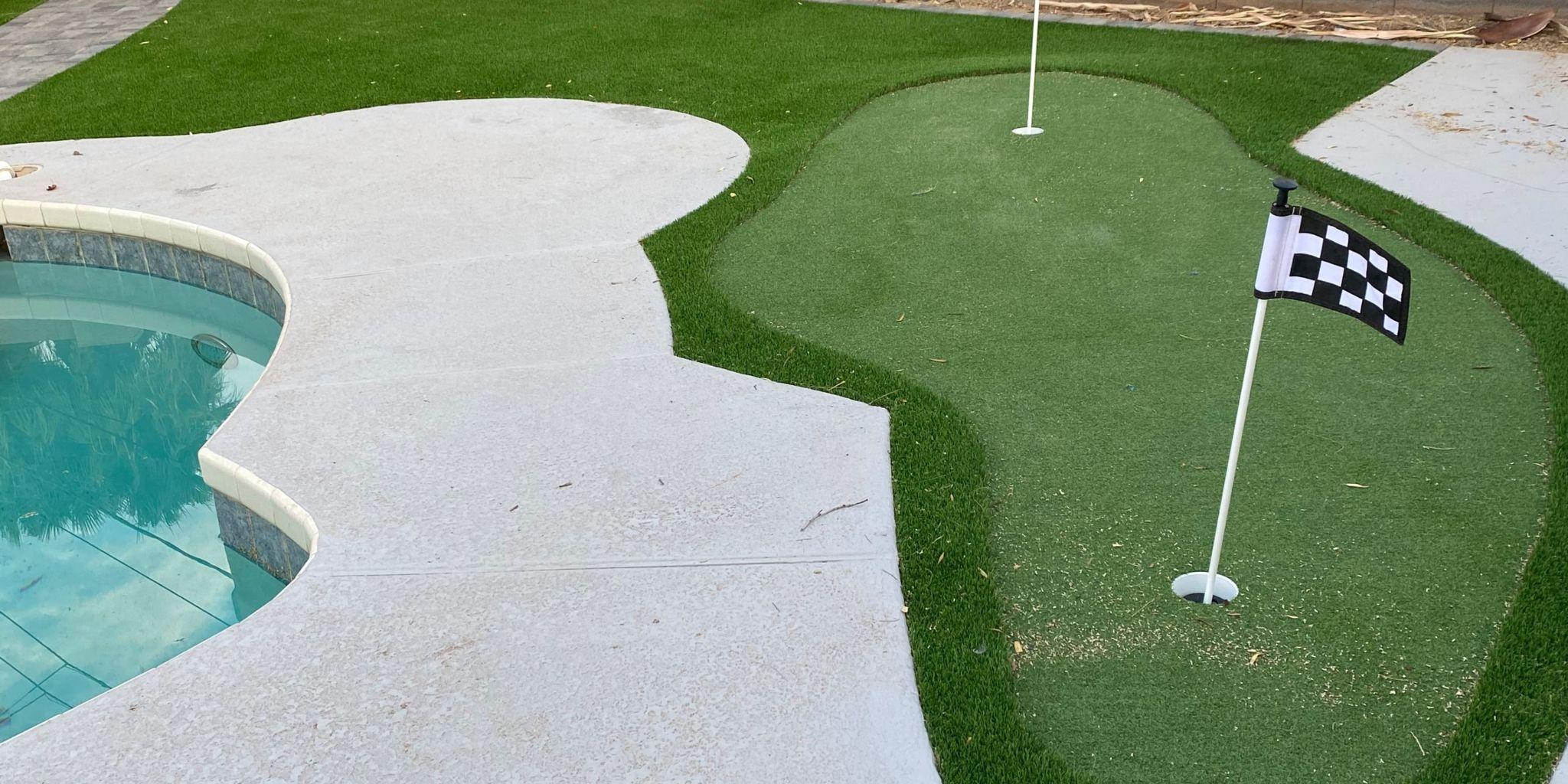 Backyard putting green beside a swimming pool.