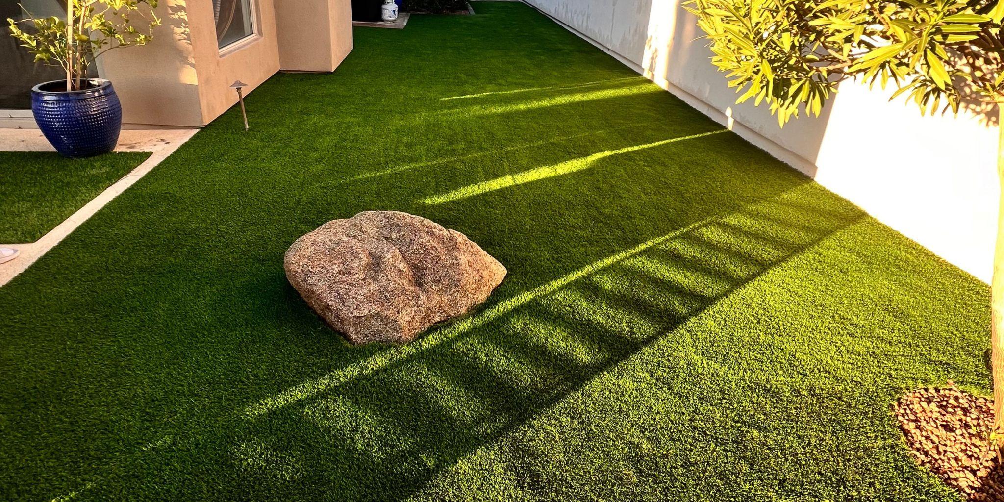 Backyard artificial turf lawn with decorative rock