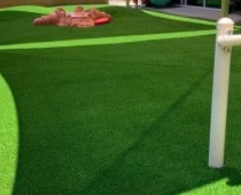 Playground with green artificial turf and white play bars
