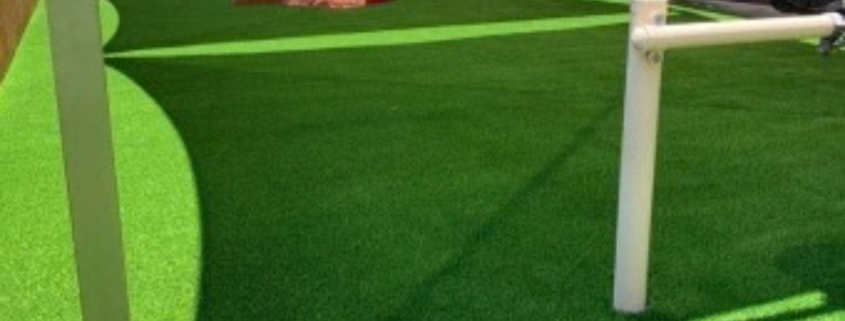 Playground with green artificial turf and white play bars