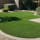 Curved artificial grass lawn bordered by stone pavers