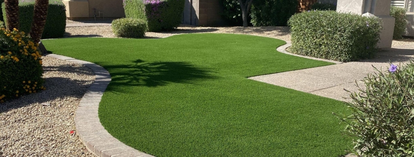 Curved artificial grass lawn bordered by stone pavers